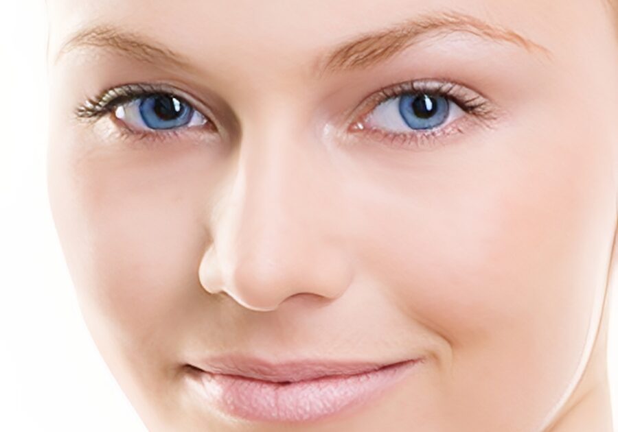 Smiling person with clear skin and blue eyes.